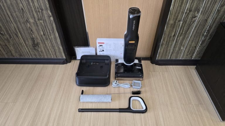 Cordless vacuum cleaner with accessories on wooden floor, cleaning tools, and instructions.